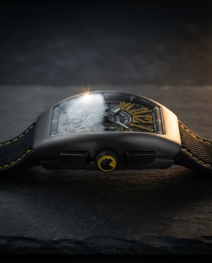 Illustrative render — reading the listing of the Franck Muller Vanguard V 45 CC DT chronograph (black titanium, black dial, yellow-outlined numerals, black leather-insert strap with yellow stitching)