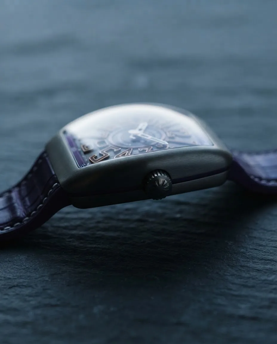 Illustrative render — reading the listing of the Franck Muller Vanguard Crazy Hours V 45 CH TT (titanium, grey dial, orange-outlined numerals, purple flange, purple alligator-grain strap)